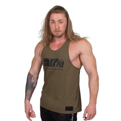 Man i Gorilla Wear Classic Tank Top Army Green, ett armégrönt brottarlinne i bomull med svart bröstlogga., bild 2 av 5