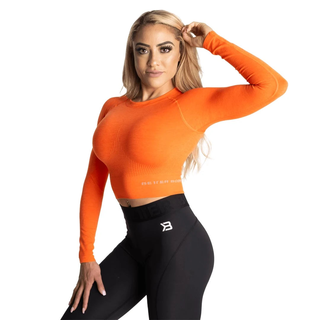 Better Bodies Rib Seamless Crop LS Sunset Melange är en orange, ribbad och långärmad träningströja buren av en modell.
