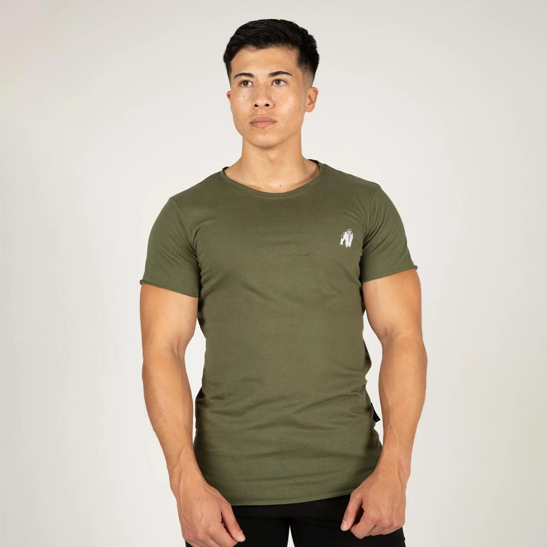 Gorilla Wear York T-Shirt Green, en kroppsnära grön t-shirt i bomull med vid halslinning, buren av en man.