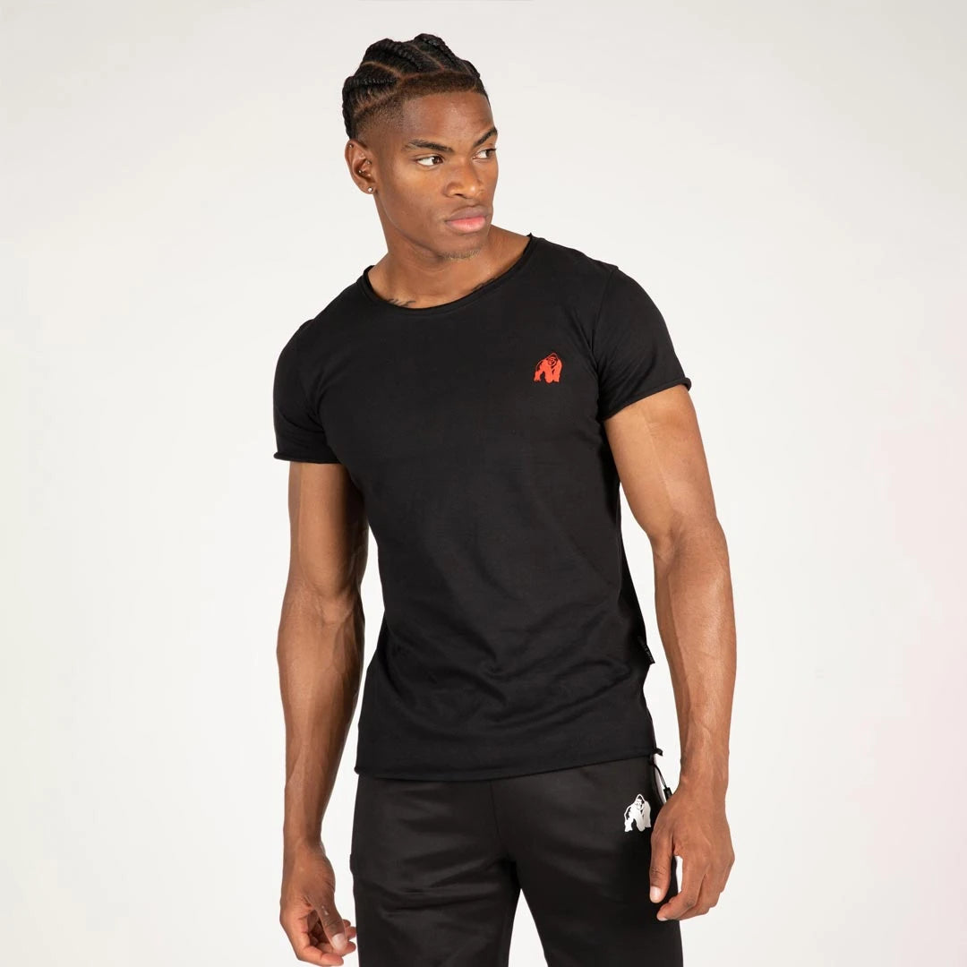 Man iklädd Gorilla Wear York T-Shirt Black i mjuk bomull med röd logotyp, slim fit och råa kanter.