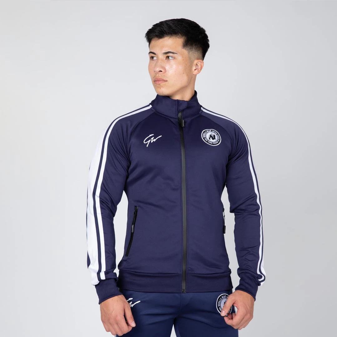 Gorilla Wear Stratford Track Jacket Navy, en marinblå träningsjacka med vita revärer på en manlig modell., bild 4 av 8