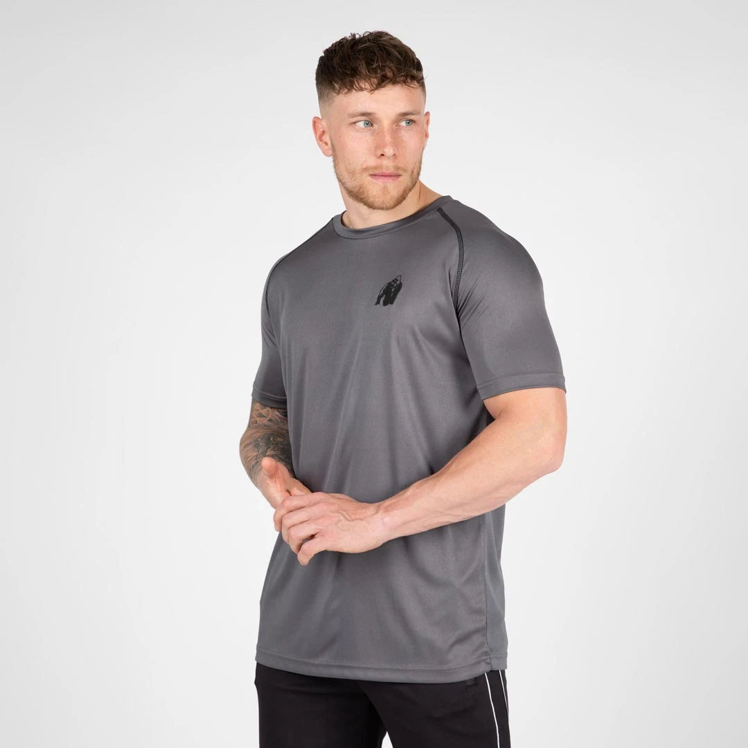 Gorilla Wear Performance T-Shirt grey, en grå träningströja med raglanärmar och svart logga buren av en man., bild 6 av 7