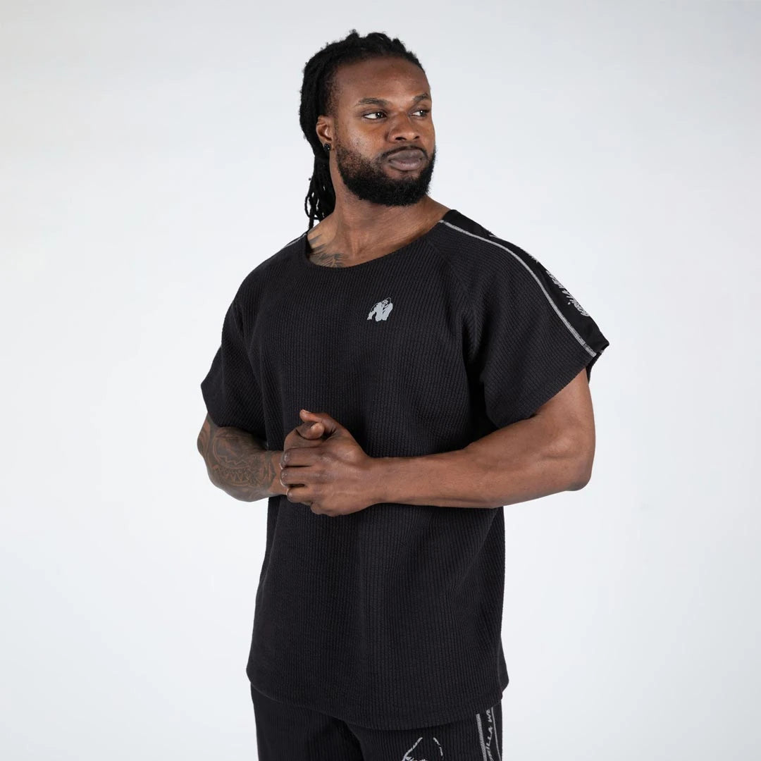 Man bär Gorilla Wear Buffalo Old School Workout Top black/grey, en ribbstickad träningstopp med oversized passform., bild 3 av 5
