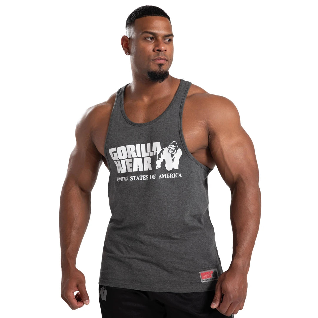 Man i Gorilla Wear Classic Tank Top Dark Grey, ett brottarlinne i bomull med stort vitt logotyptryck framtill., bild 4 av 7
