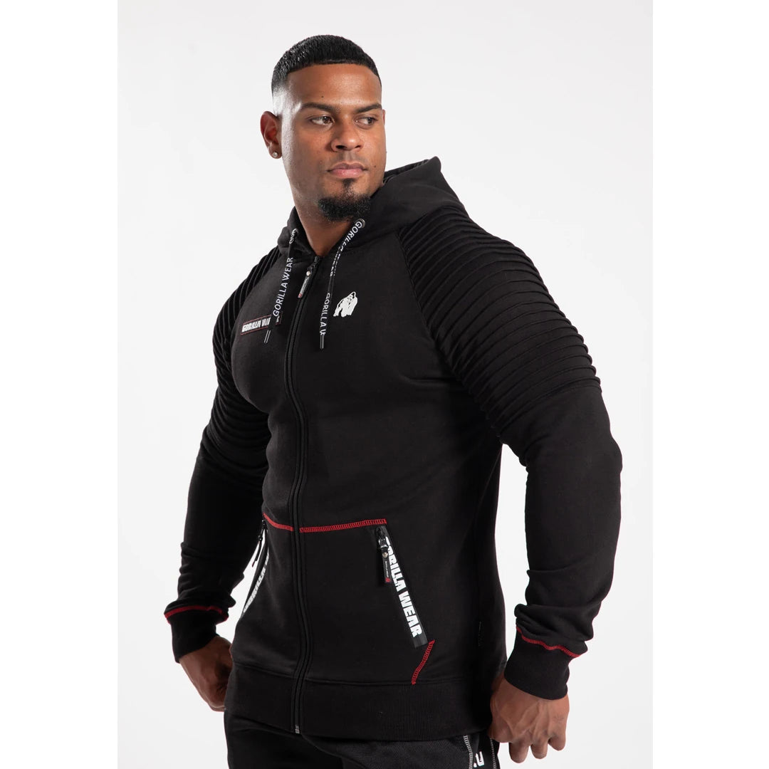 Man i Gorilla Wear Georgia Zipped Hoodie Black, en svart huvtröja med dragkedja, ribbade axlar och röda detaljer., bild 4 av 8