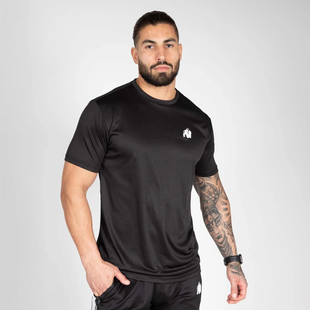 Gorilla Wear Fargo T-Shirt Black, en svart träningströja i luftig polyester med vit logga, buren av en modell.