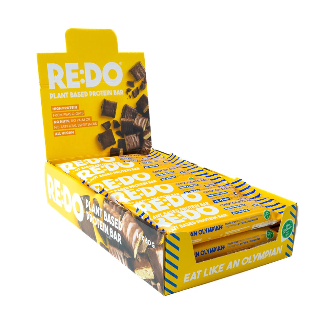 18 x REDO Bar 60 g Swedish Chocolate Ball i en gul displaykartong med veganska proteinbars i chokladbollssmak.