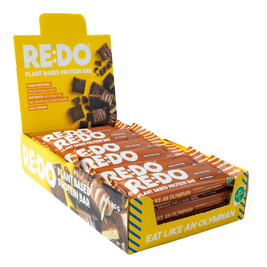 18 x REDO Bar 60 g Chocolate Chock i en öppen gul displaylåda fylld med bruna proteinbars., bild 1 av 1