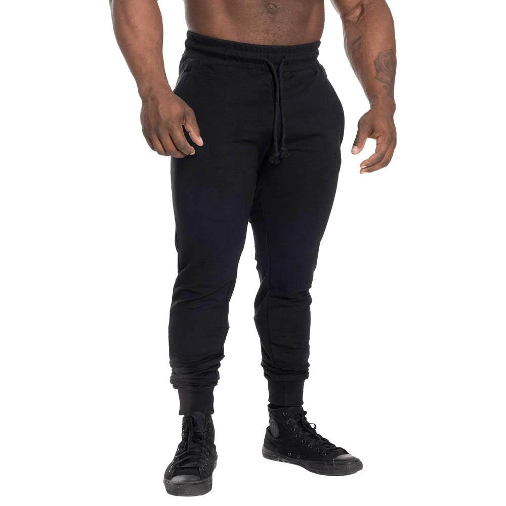 GASP Tapered Joggers Black, svarta träningsbyxor med avsmalnande passform och dragsko i midjan, burna av en modell.