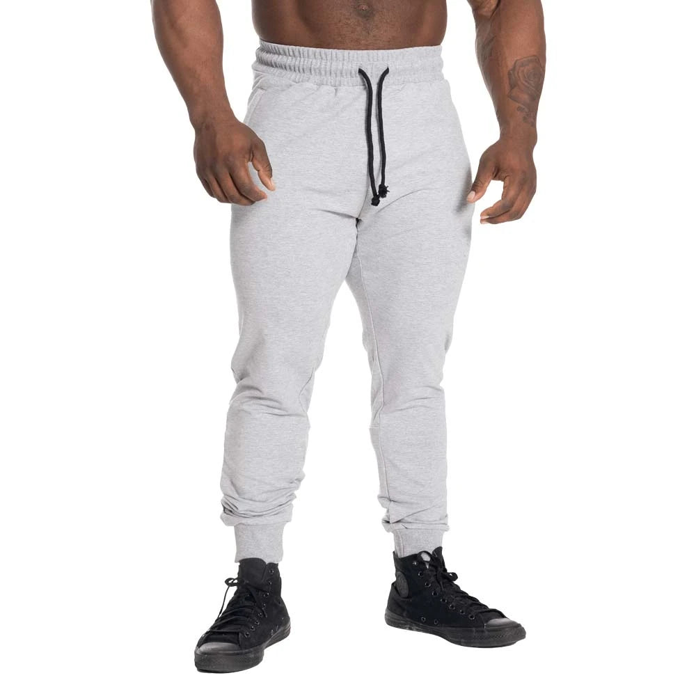 GASP Tapered Joggers Light Grey Melange är ljusgrå träningsbyxor med avsmalnande passform och svart dragsko., bild 1 av 2